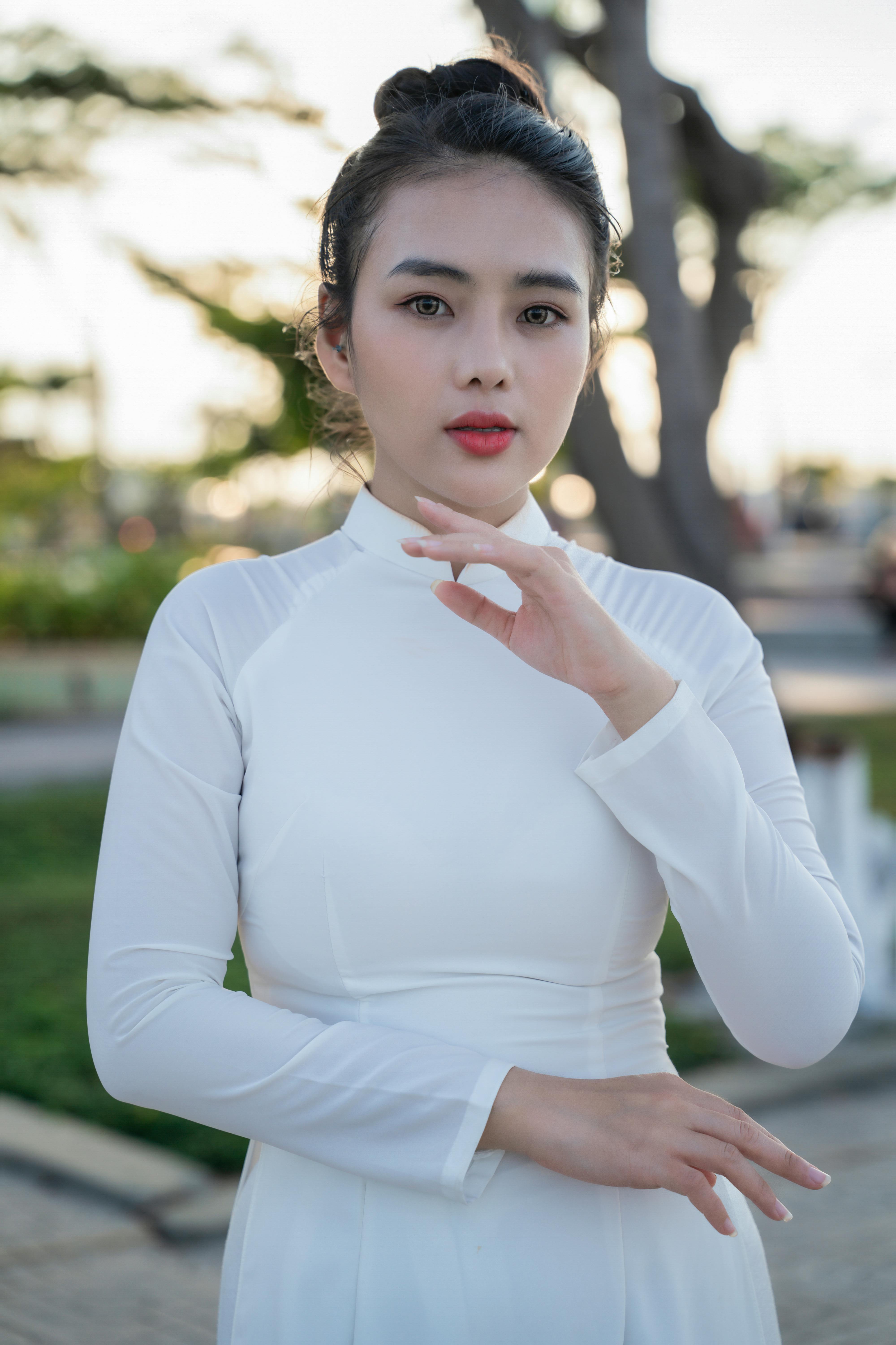Stunning portrait of a woman in a white dress against an outdoor backdrop, capturing elegance and style.