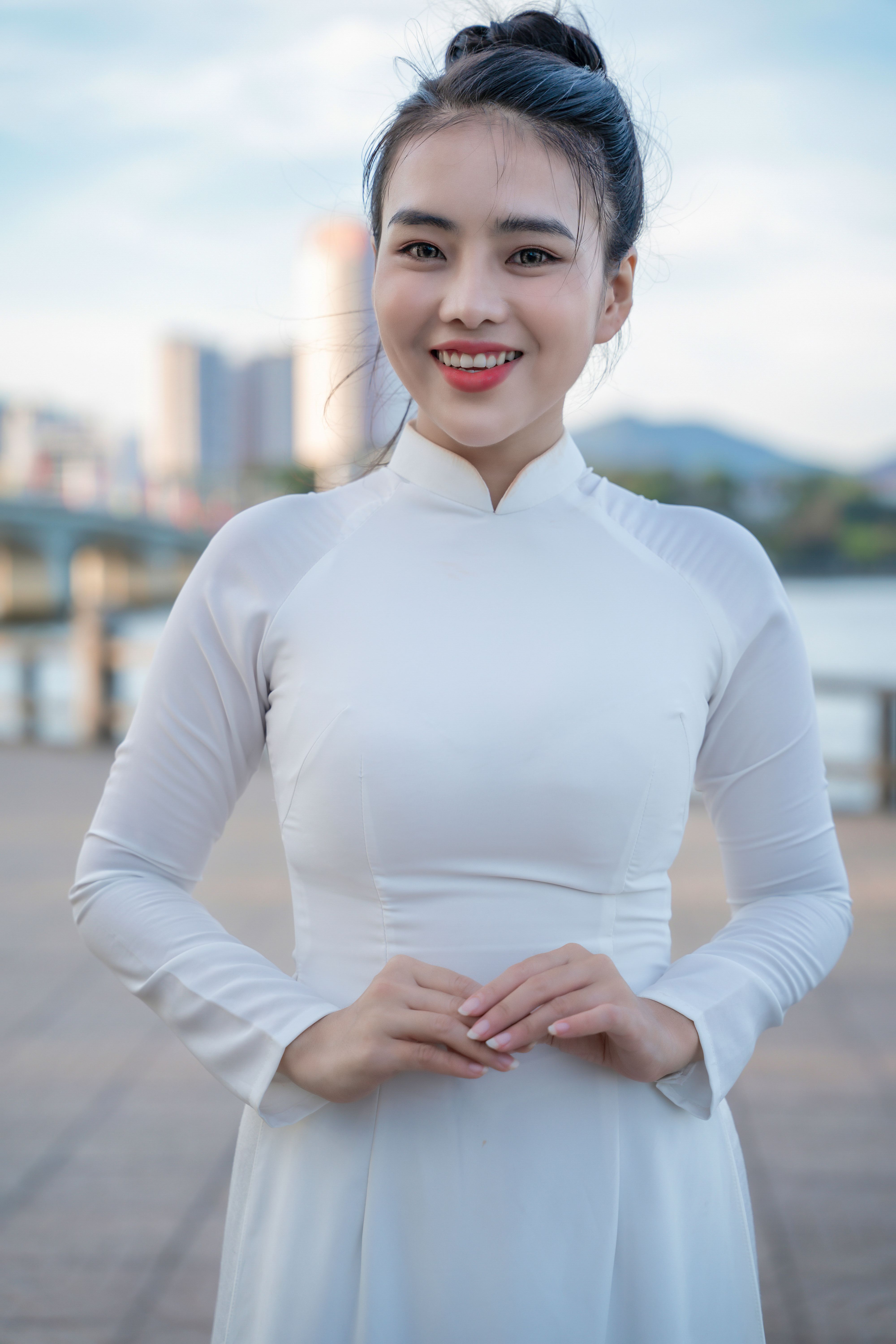 Elegant woman in an ao dai smiles brightly with an urban backdrop. Vibrant capture of culture.