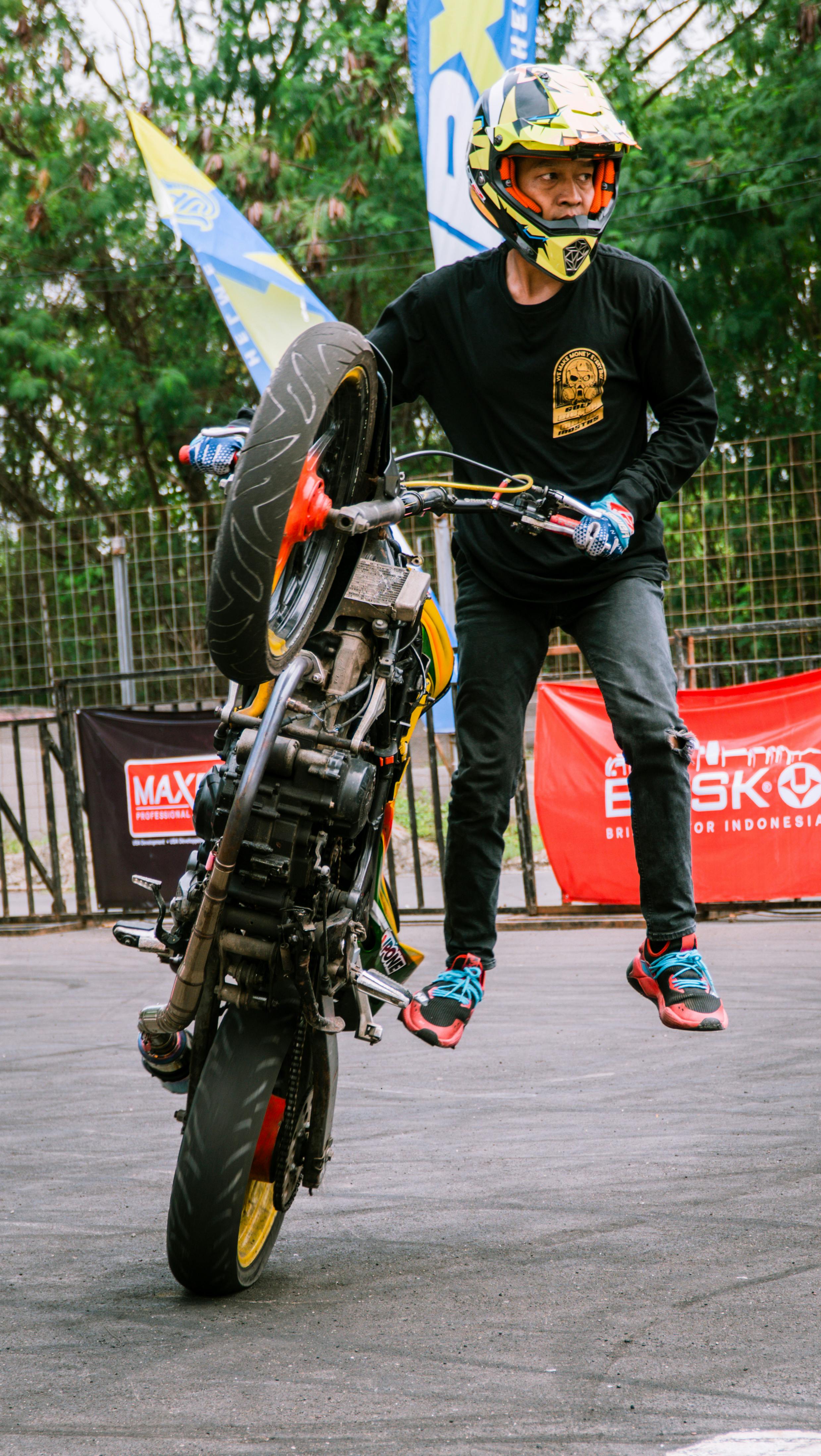 Motorcyclist performing a thrilling wheelie stunt at an outdoor event in Jakarta.