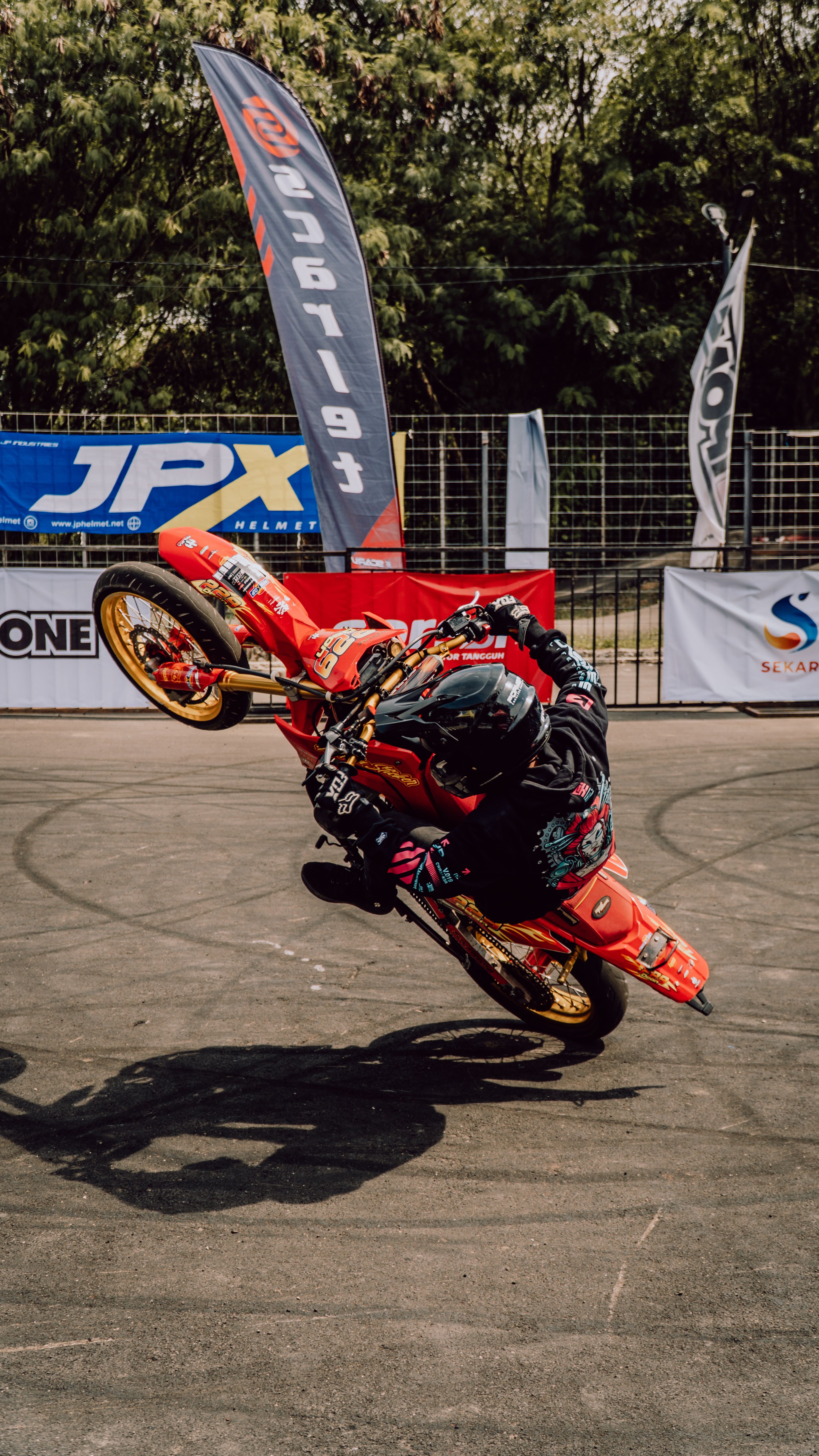 Daring motorcycle stunt performance at an outdoor event in Jakarta, Indonesia.