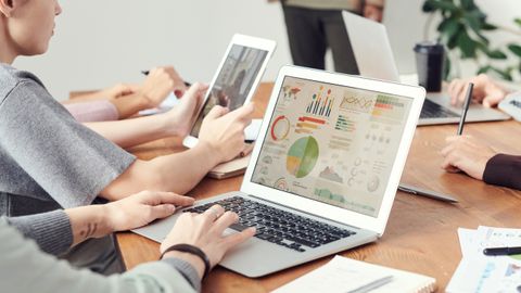 Coworkers analyzing data charts on laptops during a team meeting.