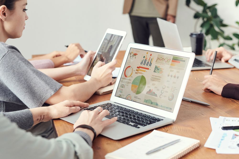 Profissionais analisando gráficos em notebooks durante reunião