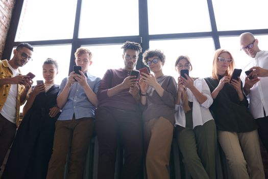 A diverse group of adults using smartphones in a modern indoor setting, fostering social interaction.