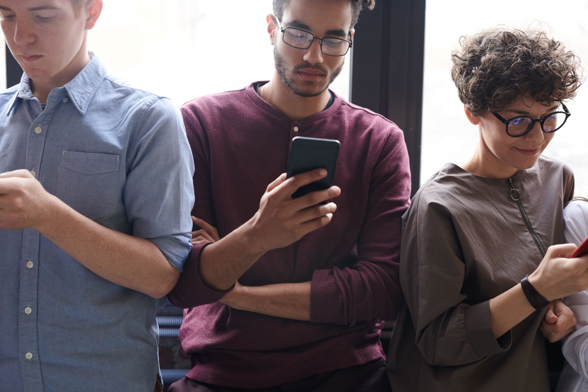A diverse group of people actively using smartphones indoors. Modern technology and social interaction.