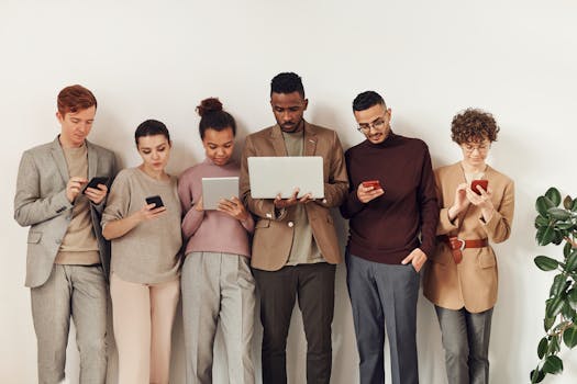 A diverse group of adults interacting with various devices in a stylish office setting, showcasing modern technology use.