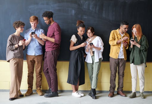 多元化的年轻人站在黑板前，用智能手机展示技术与连接