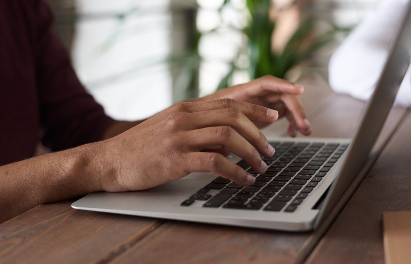 Hands of a person typing on a laptop keyboard indoors, ideal for remote work and freelancing themes.