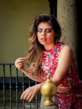 Elegant woman with vibrant makeup and floral dress striking a pose in an outdoor setting.