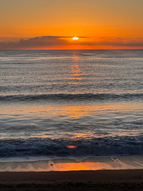 Free Captivating sunrise over tranquil ocean waves and sandy beach. Stock Photo