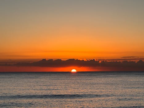 Serene ocean sunrise with vivid orange hues and gentle waves.