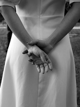 Elegantly dressed woman with hands clasped in a serene pose, captured from behind.