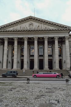 Elegant building with a pink limousine parked in front, showcasing classic architecture.