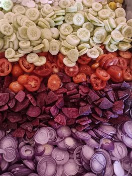 Vibrant assortment of sliced cucumbers, tomatoes, beets, and onions arranged in layers.