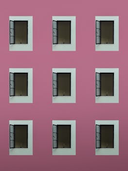 Artistic grid of windows on a vibrant pink wall in Guadalajara, Mexico.
