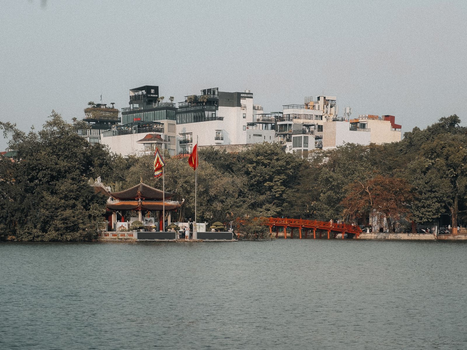 Scenic view of Hoàn Kiếm Lake with the iconic red bridge and vibrant cityscape in Hanoi, Vietnam.