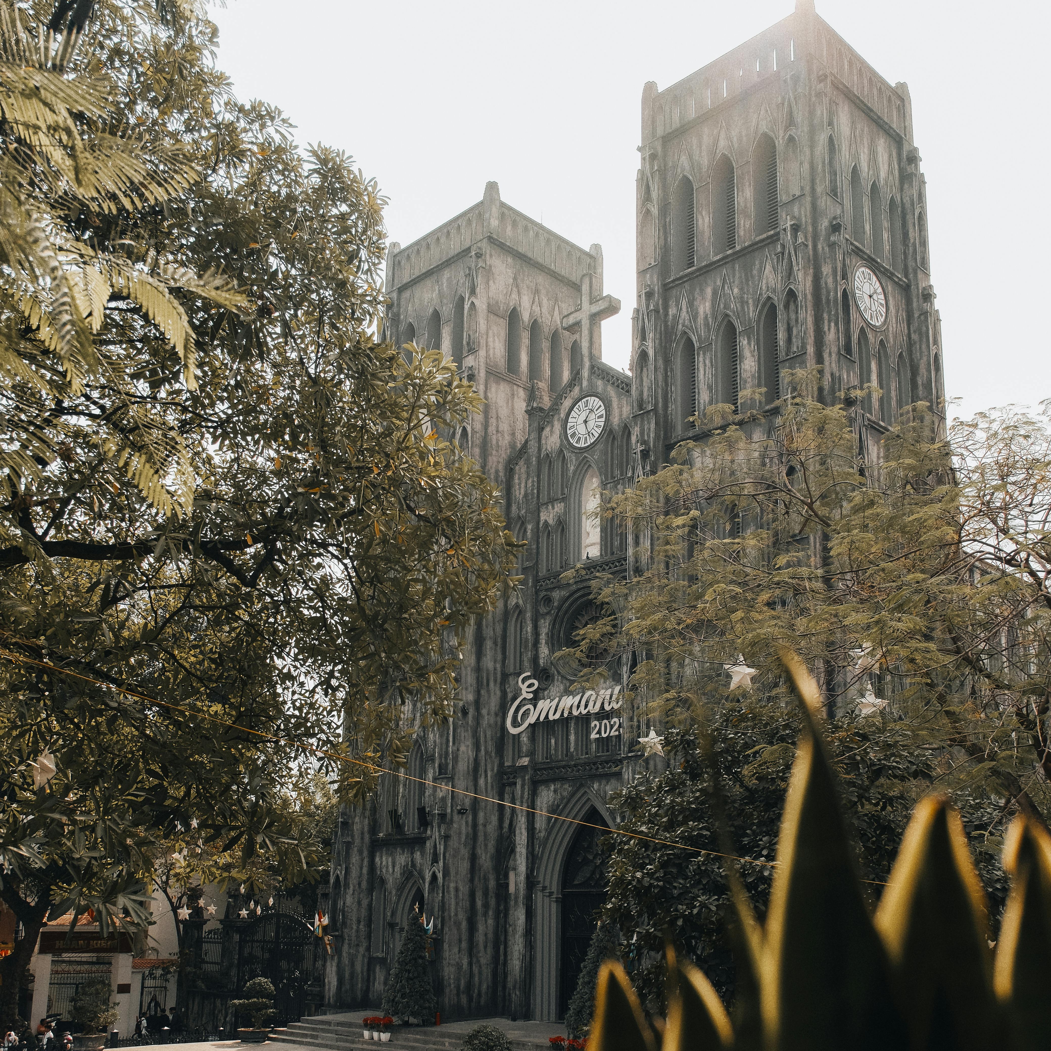 Gothic-style St. Joseph's Cathedral in Hà Nội surrounded by lush greenery on a sunny day.