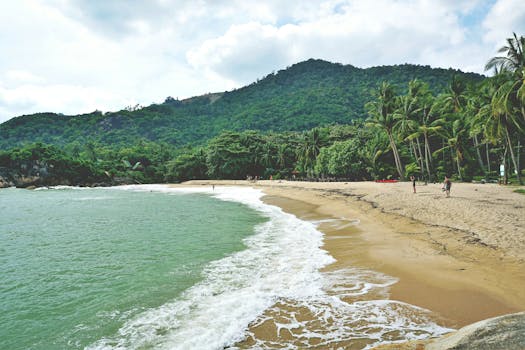 Explore the tranquil beach at Ban Tai, Thailand, with lush greenery and golden sands.