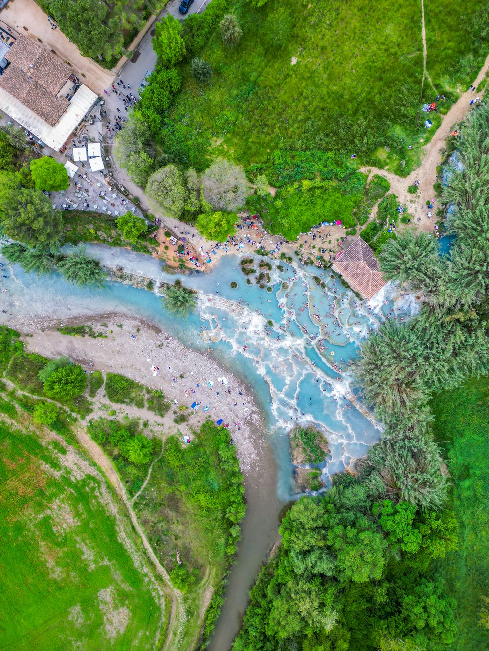 Vedere de sus asupra izvoarelor termale de la Saturnia, cu bazine albe și apă albastră
