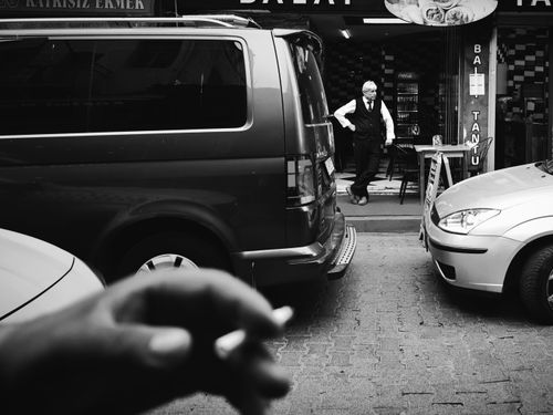 Free Black and white photo capturing a man in a door and hand holding a cigarette in İstanbul street. Stock Photo