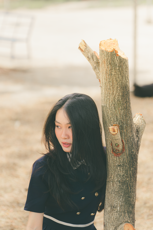 Woman Standing By Tree Trunk in Sunlit Park · Free Stock Photo