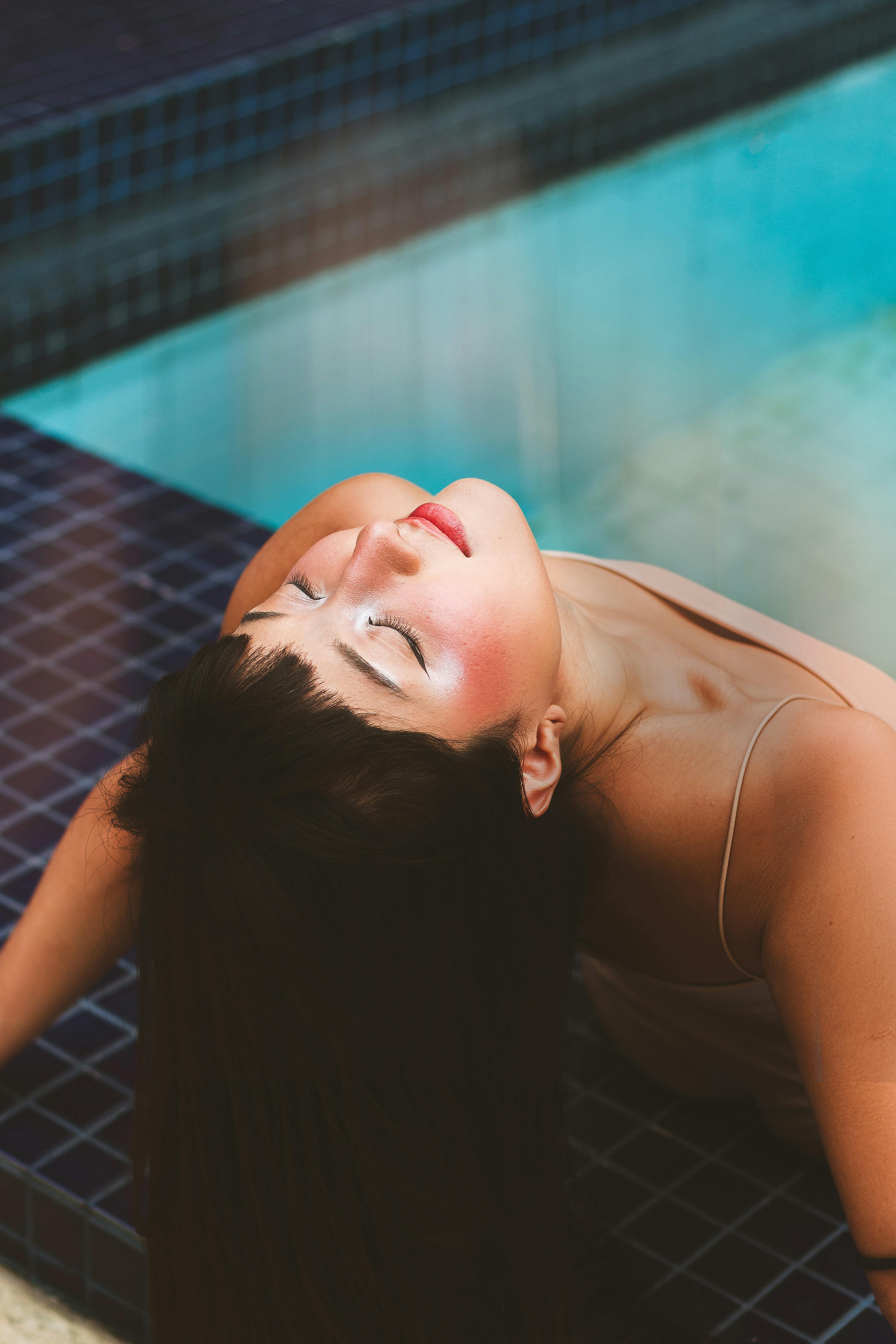 A woman enjoying relaxation by the poolside with a warm and serene expression, located in São Paulo, Brazil.