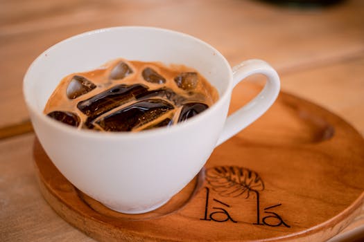 Close-up of iced coffee served in a white cup on a wooden tray at a café in Bien Hoa, Vietnam.