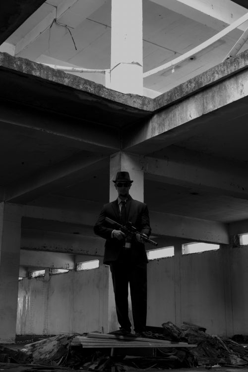 Free A man in a black suit and hat stands in an abandoned building, creating a mysterious ambiance. Stock Photo
