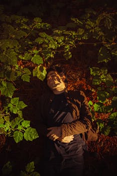 Relaxed man lying in sunlit forest surrounded by lush greenery.