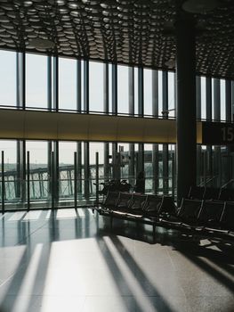 Spacious airport terminal with large windows casting dramatic sunlit shadows.