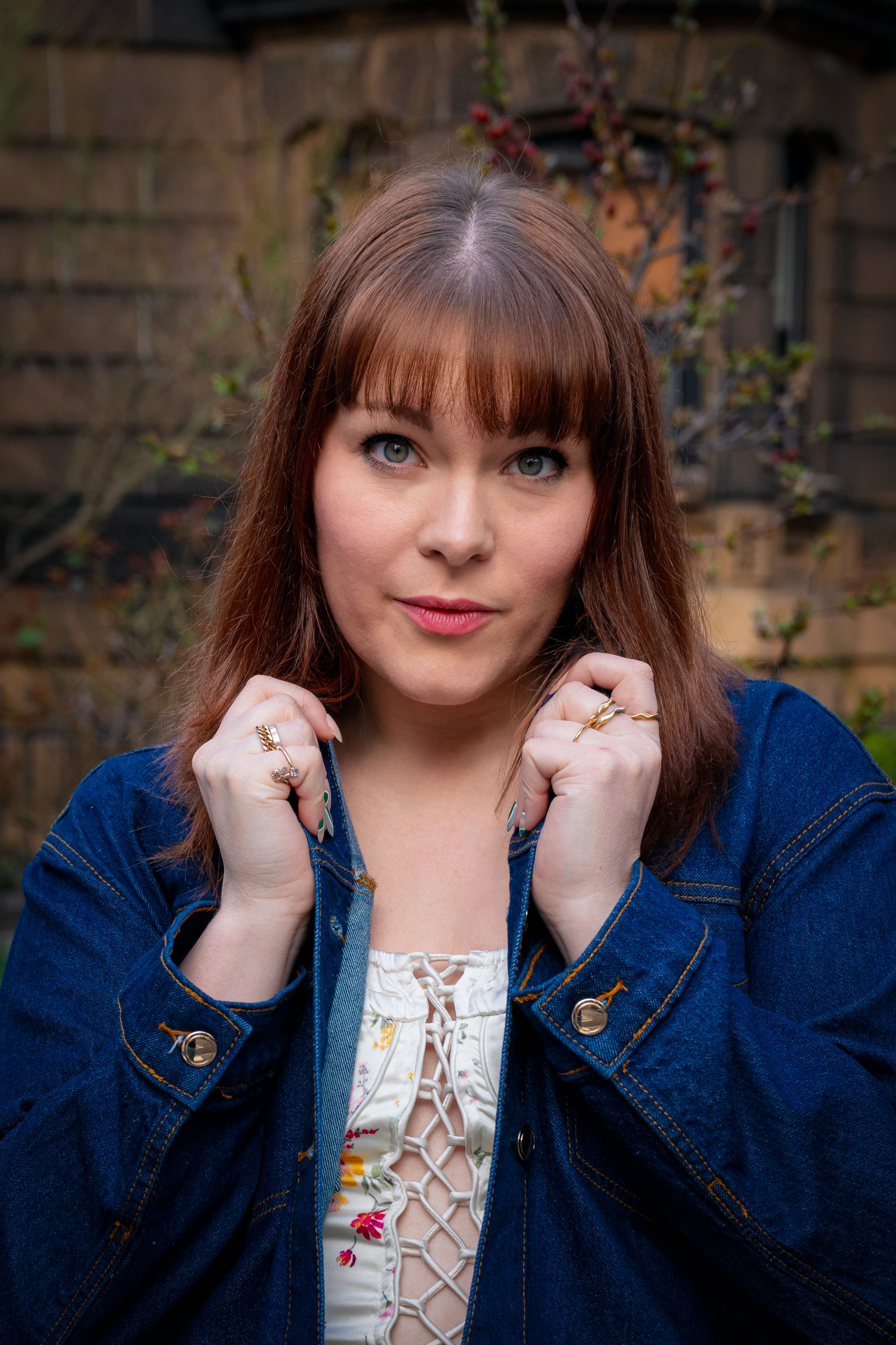Portrait of a woman in a denim jacket posing confidently outdoors in Soho, New York City.