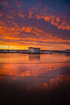 Vibrant sunrise reflecting over Lake Powell Marina in Arizona, showcasing dramatic clouds and tranquil water.