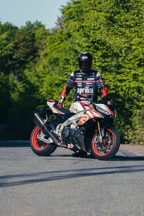 Free A motorcyclist in gear riding a sportbike on a sunny day surrounded by greenery. Stock Photo