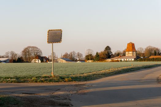 Idyllic countryside scene featuring a rural road and distant village buildings in Germany during daylight.