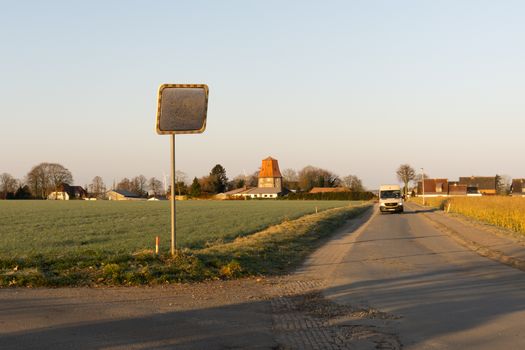 Scenic rural road in Germany with a windmill in the background on a clear day.