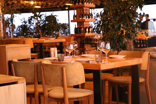 Warm restaurant interior showcasing a set dining table with wine glasses and elegant decor.