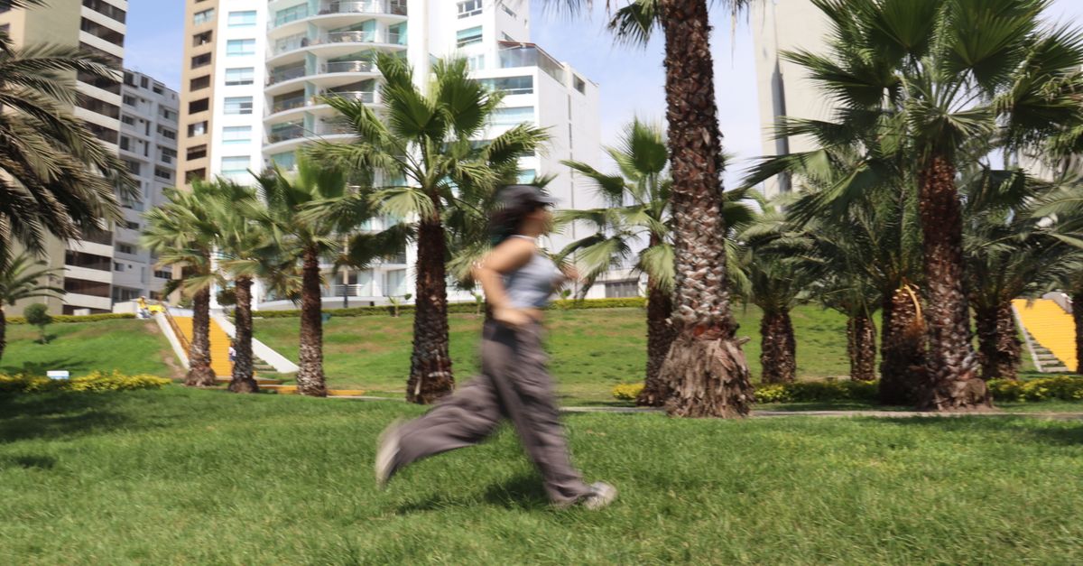 Blurred motion capture of running woman amidst palm trees in Callao, Peru.