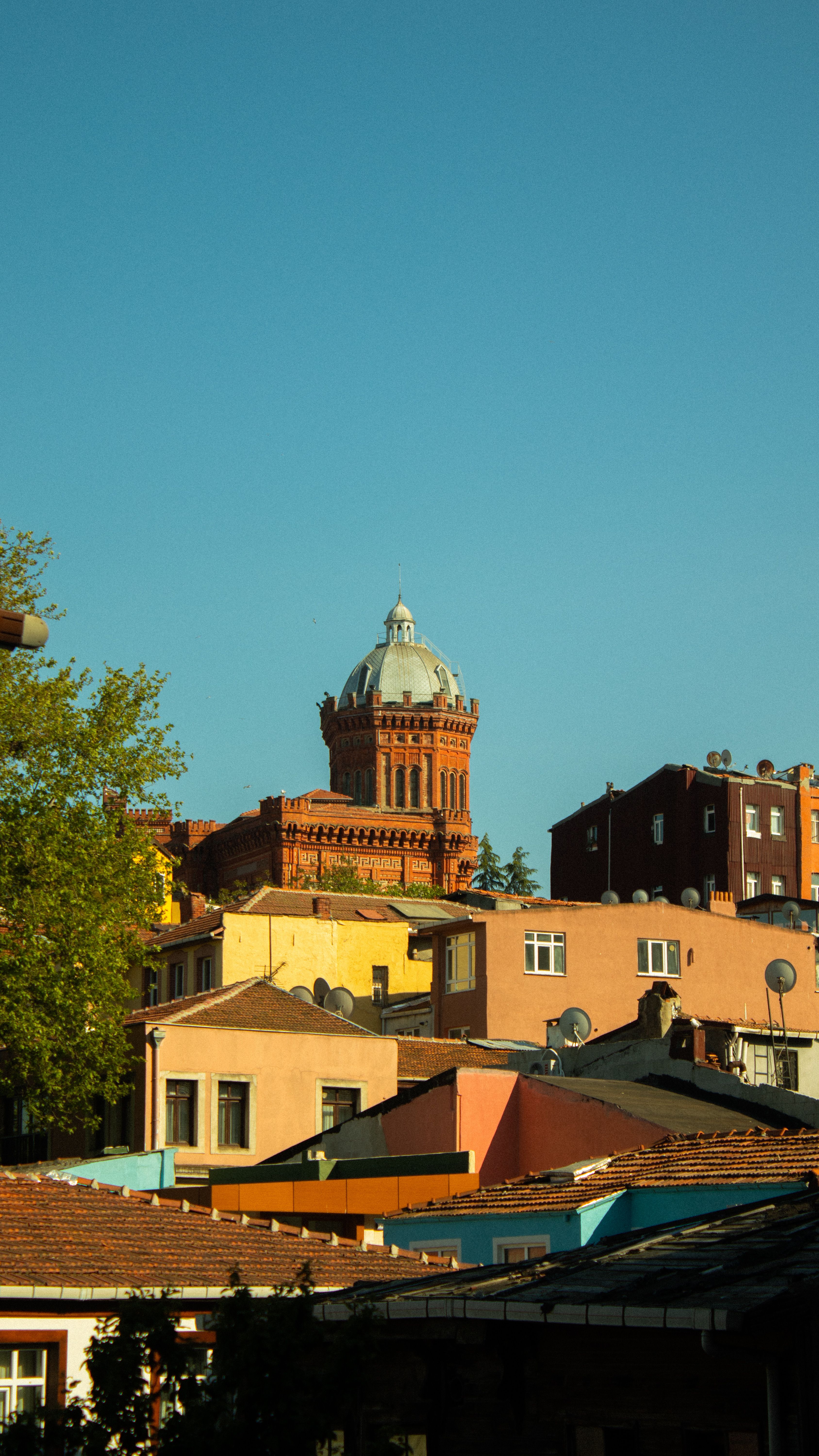 Colorful buildings in Istanbul with iconic red dome tower in background.