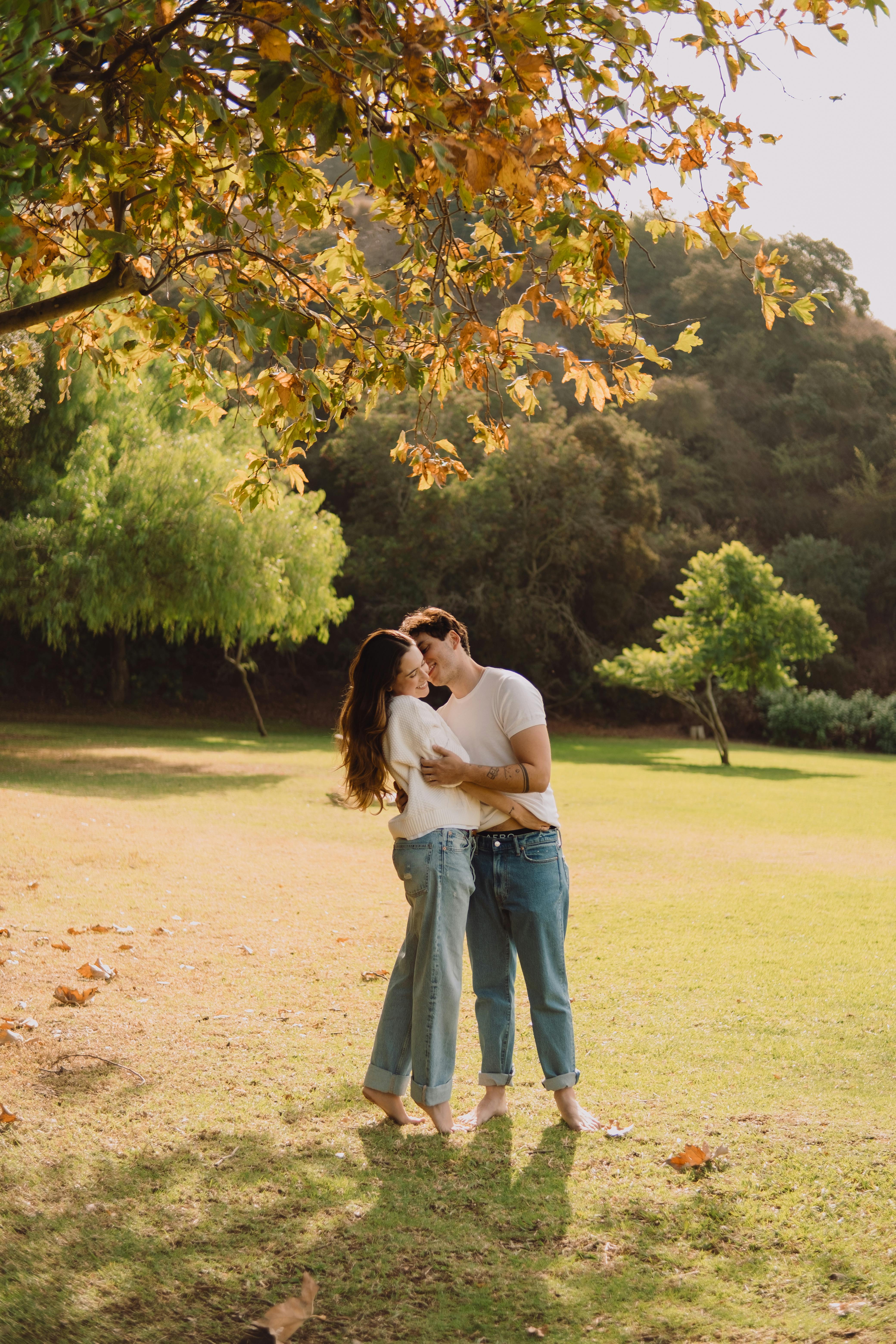A couple shares a loving embrace under autumn trees in a Los Angeles park.