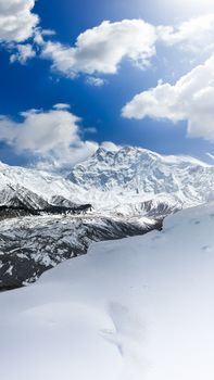 Breathtaking view of snow-covered mountains and bright blue sky in Pakistan's alpine region.