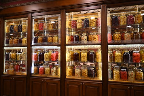 Free Vibrant shelves of preserved fruits and vegetables in glass jars on a wooden cabinet in Istanbul, Türkiye. Stock Photo