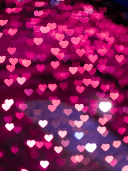 Free Abstract heart-shaped bokeh lights in warm pink tones create a romantic and dreamy atmosphere. Stock Photo