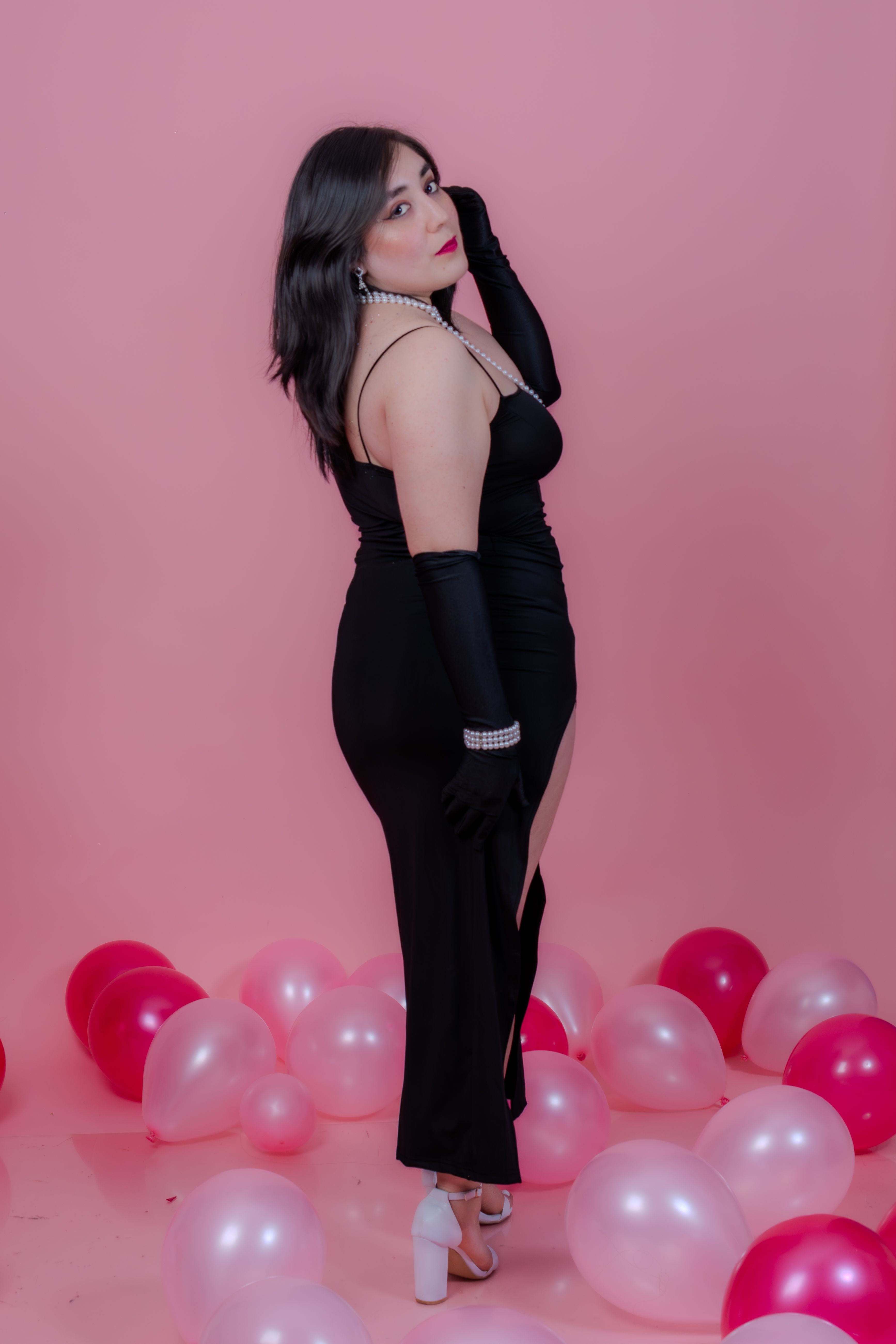 Elegant Woman in Black Dress Among Pink Balloons