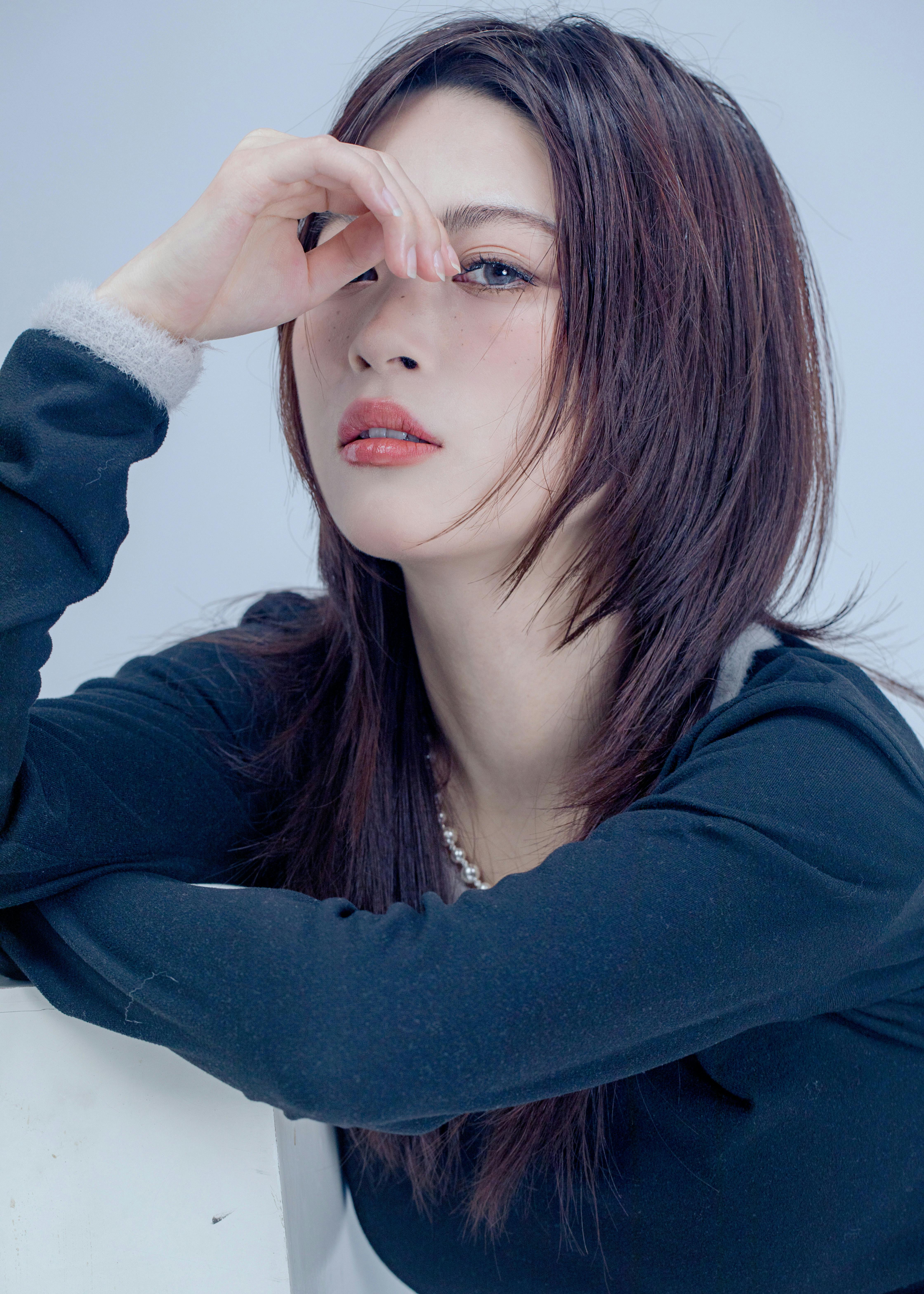 Stylish woman in black top exuding elegance and mystery with a dramatic pose.