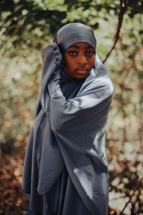 Free A woman in a hijab stands amidst lush greenery, exuding grace and tranquility. Stock Photo