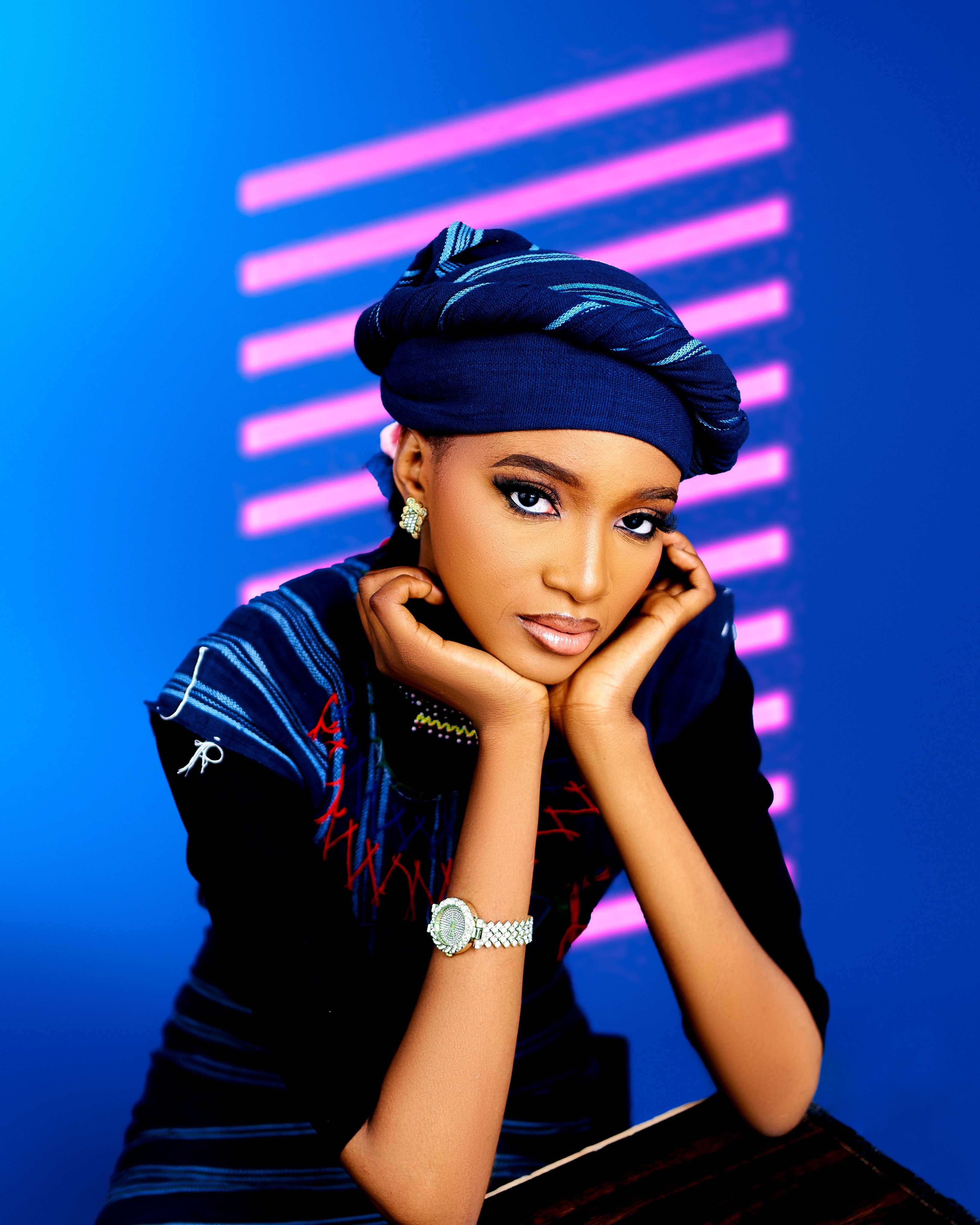 Stylish portrait of a young woman in traditional blue attire against a vibrant background.