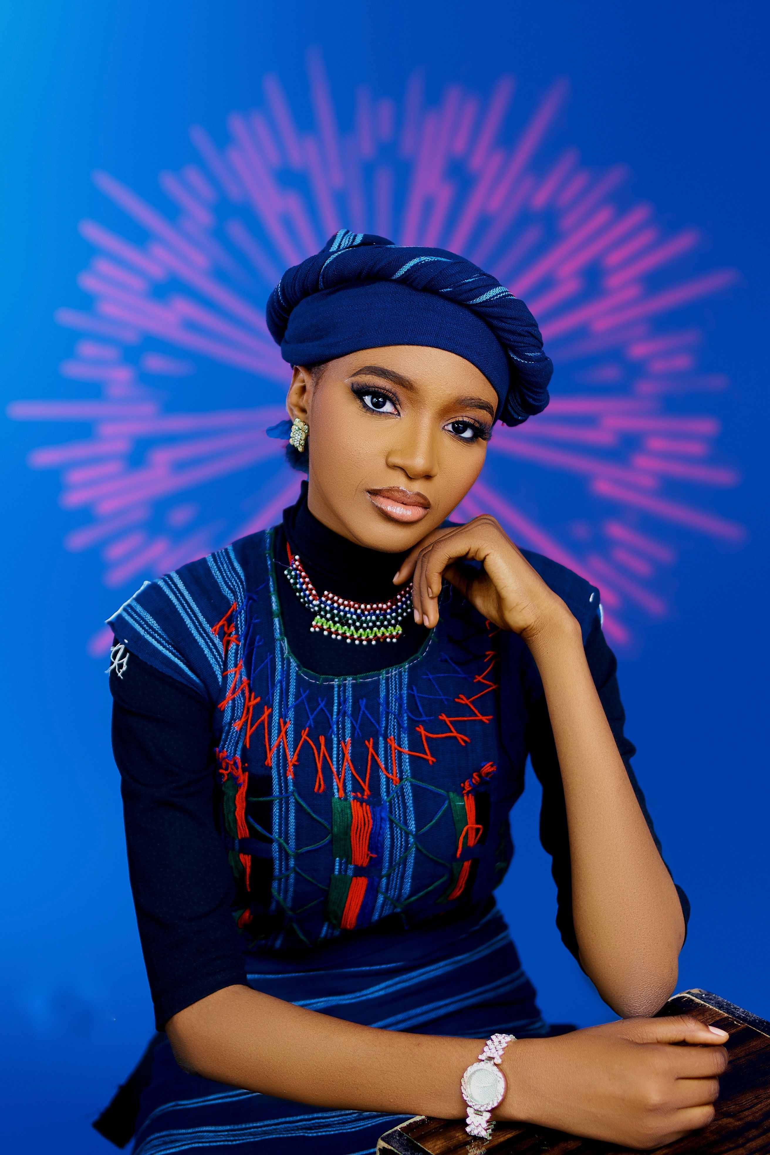 Portrait of a woman in vibrant traditional attire against a colorful backdrop.