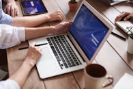 团队成员在现代化的办公空间里，一边用笔记本电脑一边喝着咖啡进行头脑风暴，以促进协作