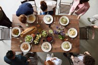 从上面看，一群人围坐在木桌旁吃饭