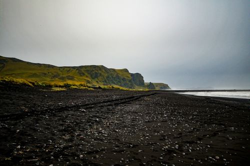 Free Explore this stunning black sand beach with dramatic cliffs under a moody sky, perfect for adventure seekers. Stock Photo