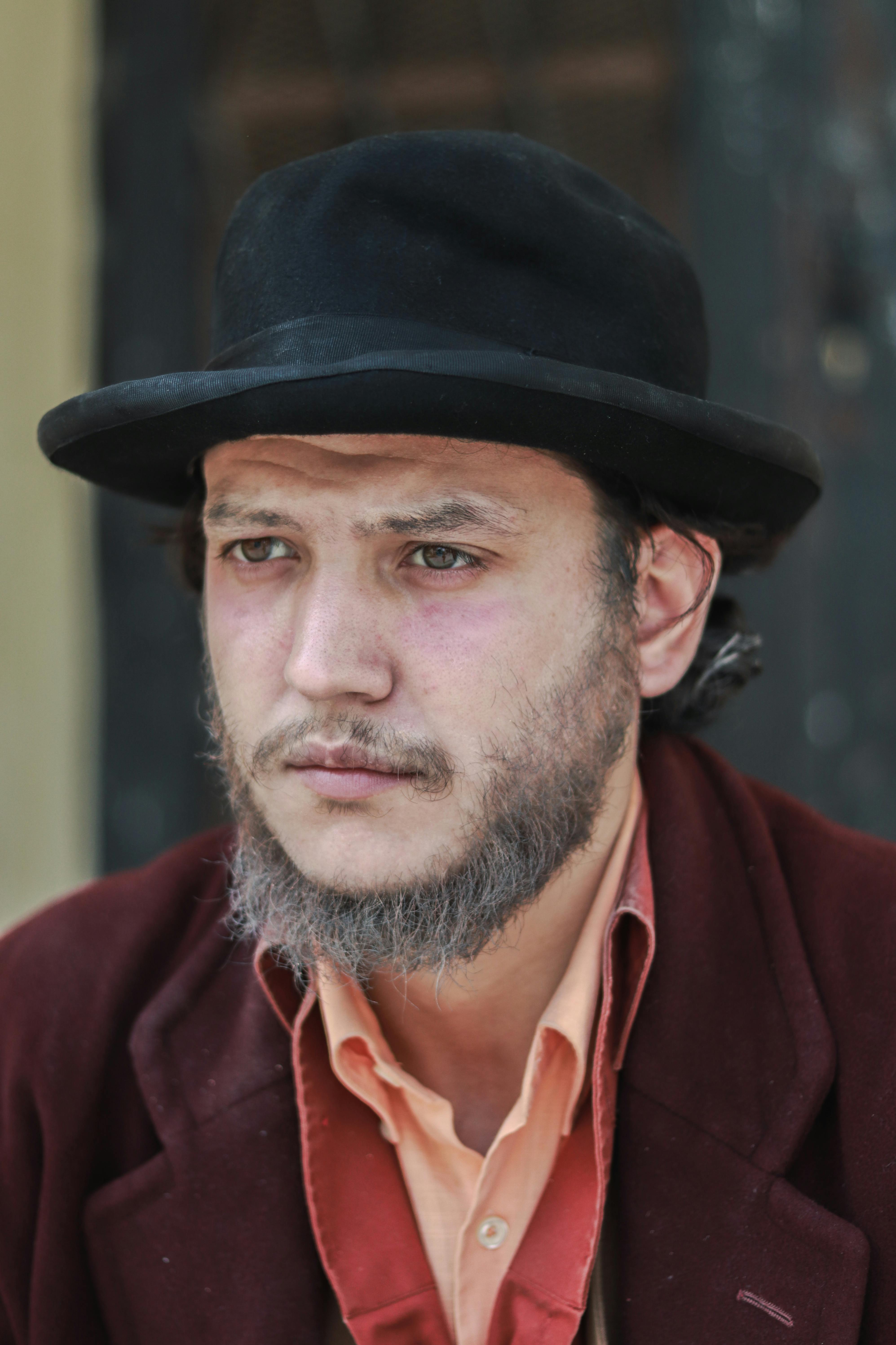 Gratuit Portrait en gros plan d'un homme barbu pensif portant un chapeau noir et un manteau rouge. Photos